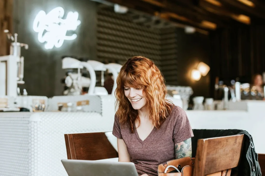 Customer relaxing with a laptop in a cafe while she waits
