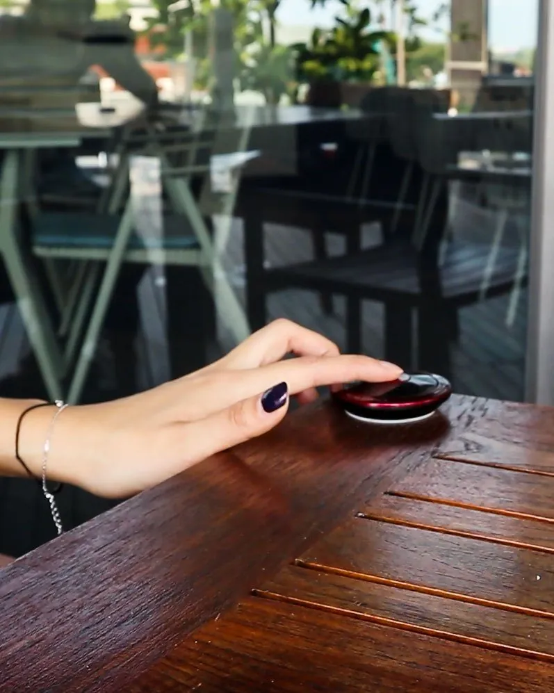 Guest pressing a wireless call button on a restaurant table