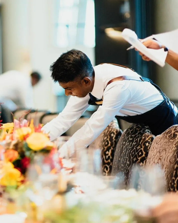 Hotel waiter setting a dining table