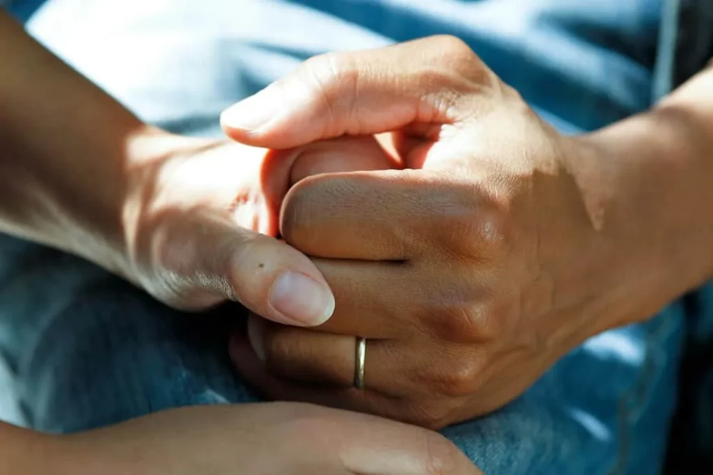Caregiver gently holding a person’s hands
