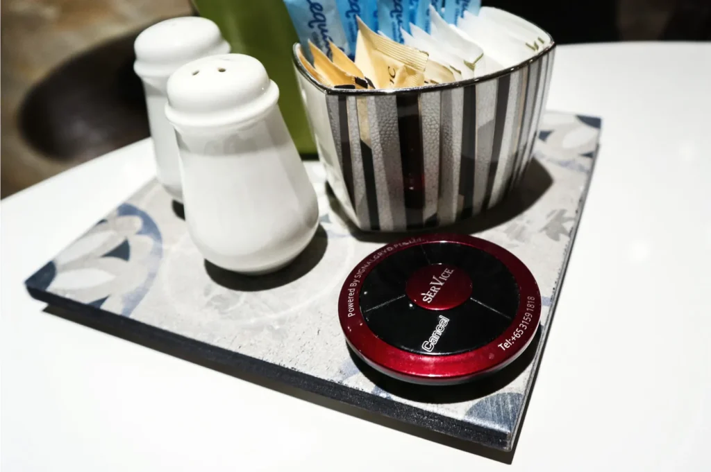 Wireless call button on a restaurant table beside salt and pepper shakers