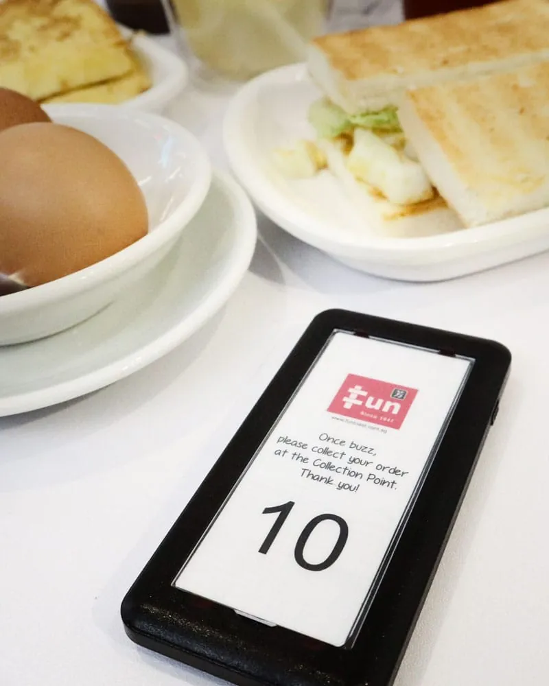 Customer pager on a table beside a breakfast of toast and eggs