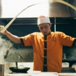 Chef preparing noodles in a restaurant kitchen