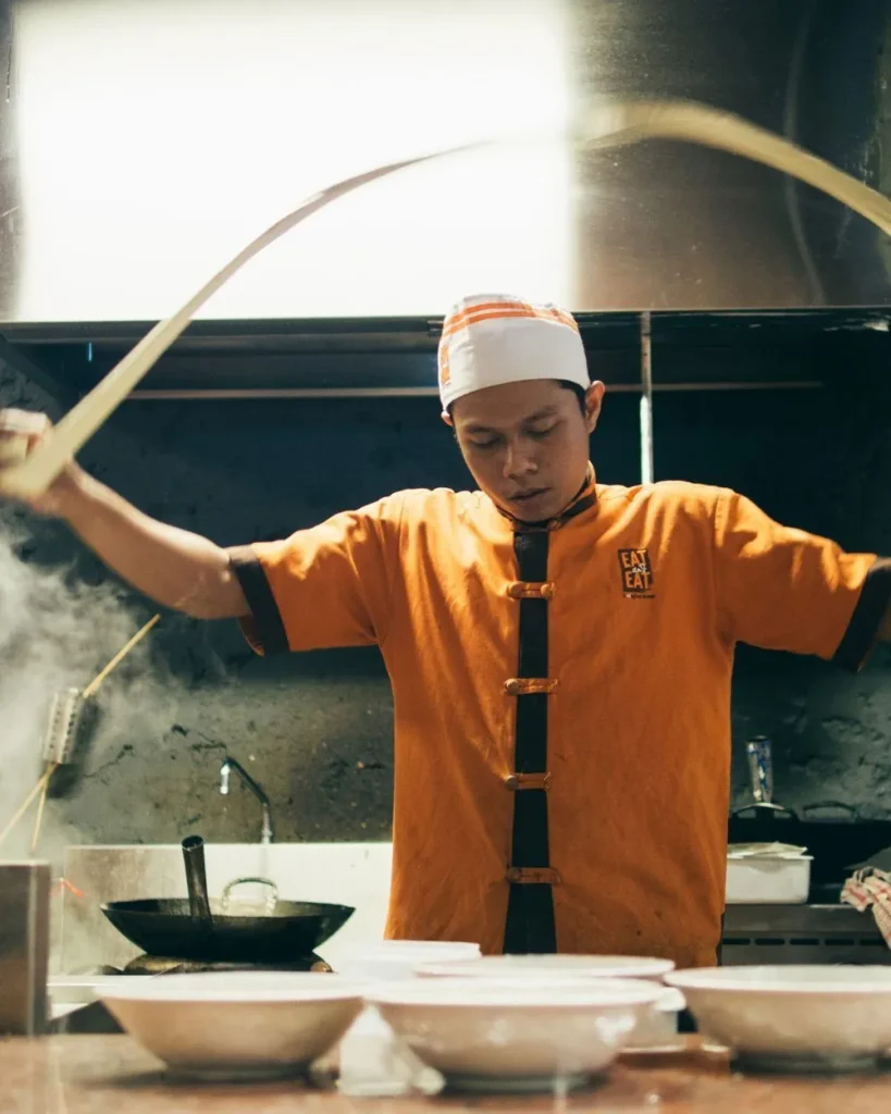 Chef preparing noodles in a restaurant kitchen