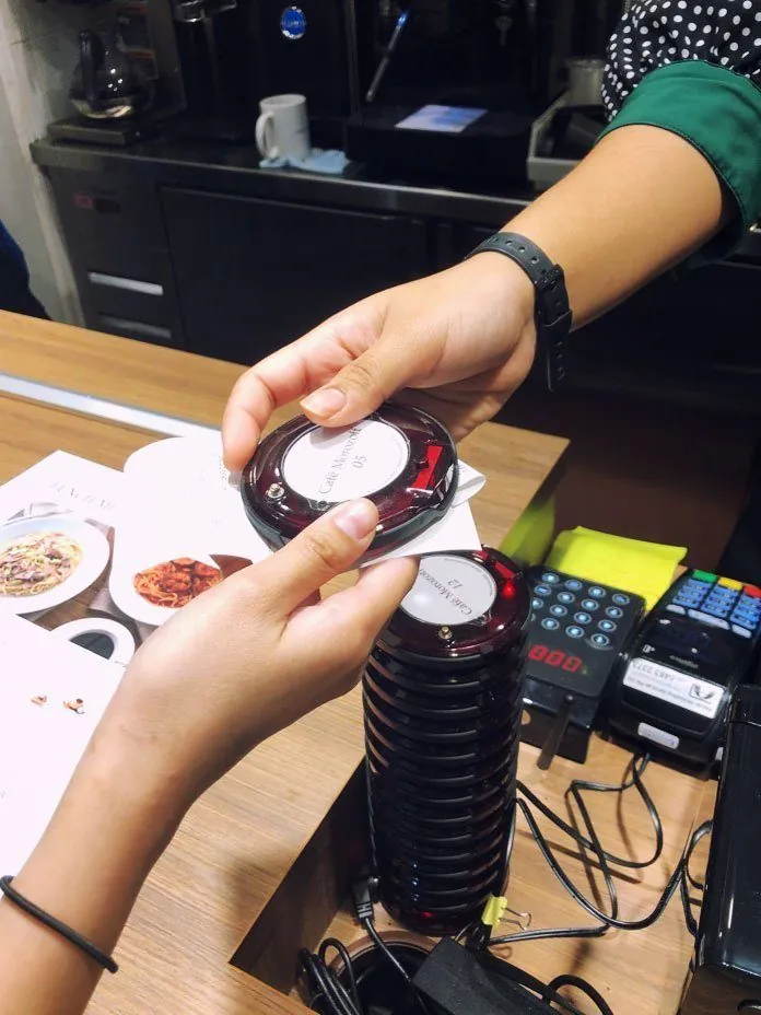 Cashier handing a Series Pacific pager to a customer