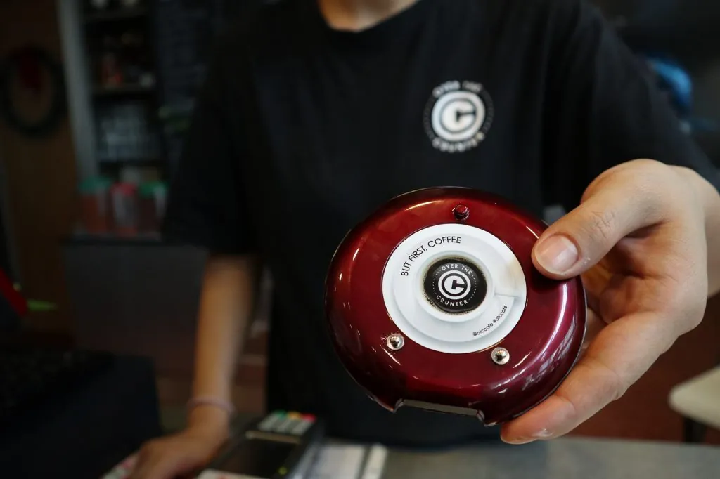 Cafe staff holding a wireless customer pager at the order counter