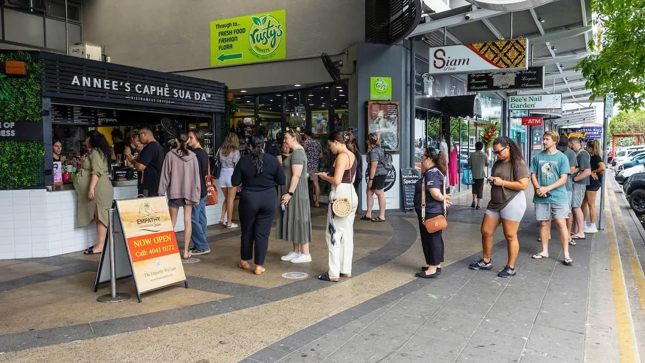 Customers queuing in a single line outside a shop