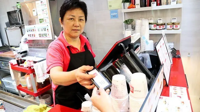 Staff member handing a Series Slim pager across the counter