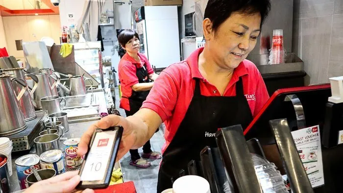 Cashier handing a Series Slim pager to a customer