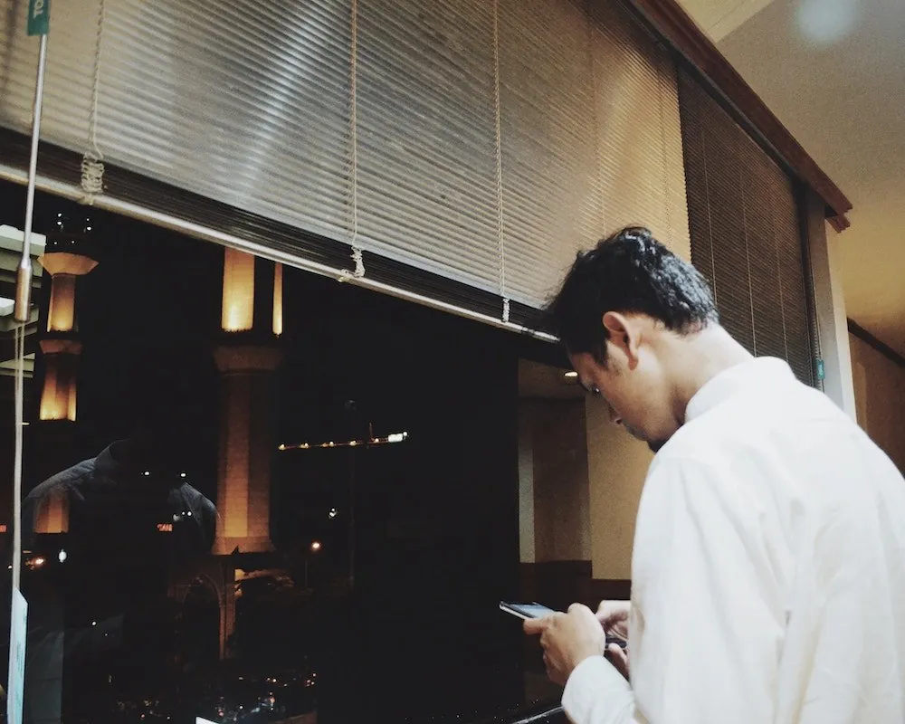 Customer checking his phone outside a restaurant at night