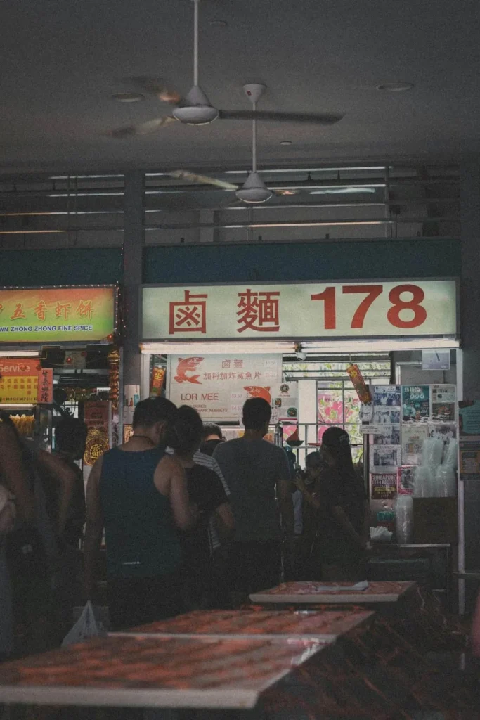 Busy hawker stall at night with a queue number signboard