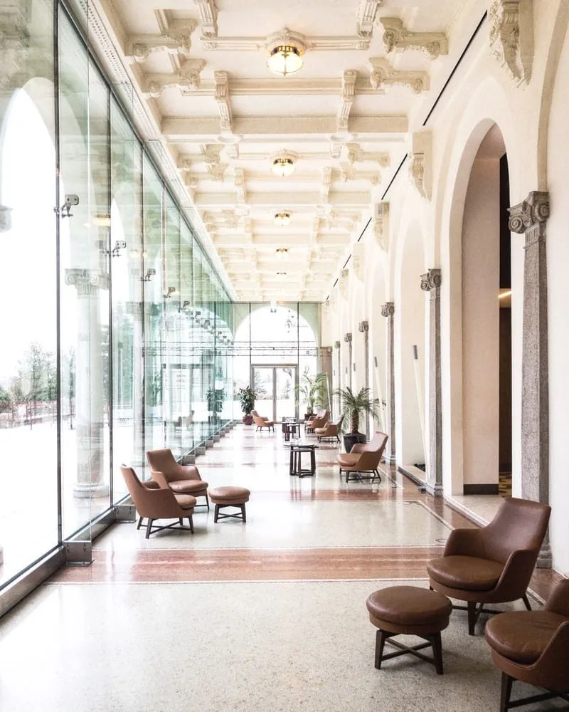 Bright hotel lobby corridor with arched windows and lounge chairs