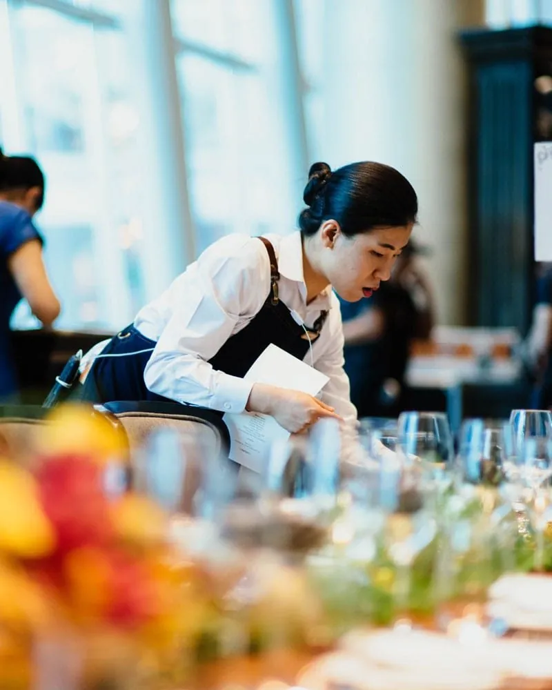 Hotel staff member setting a dining table